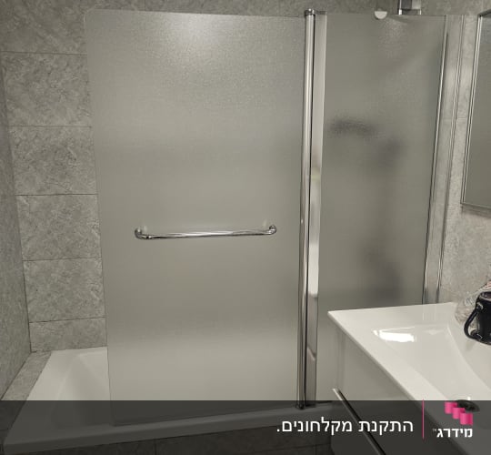 אמבטיון זכוכית חלבית מותקן על אמבטיה בחדר רחצה מרוצף